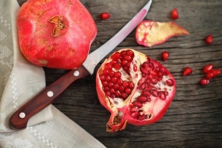 Juicy riped pomegranate and knife on the wooden table.jpg