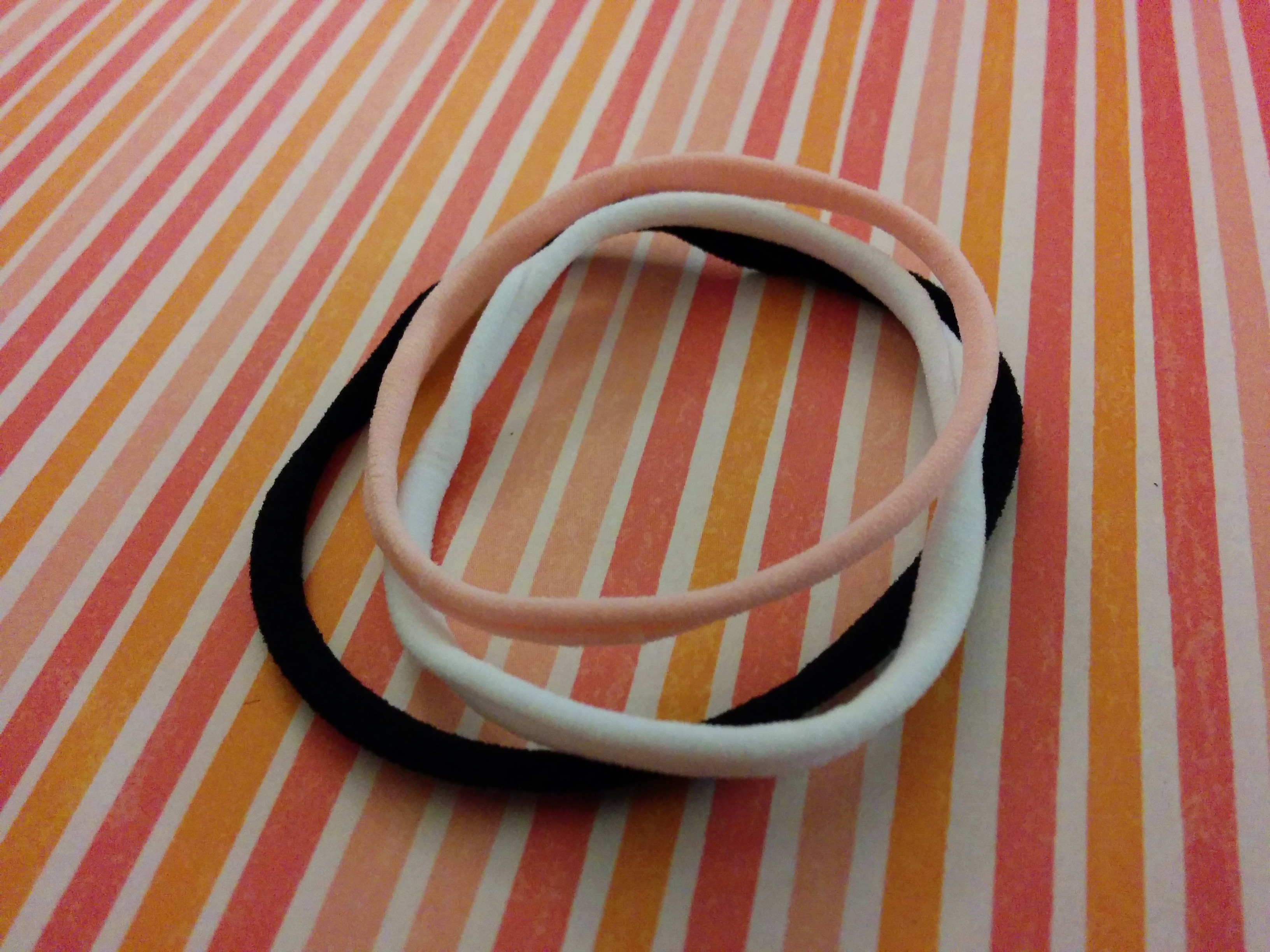 three skinny hair ties on striped paper.jpg