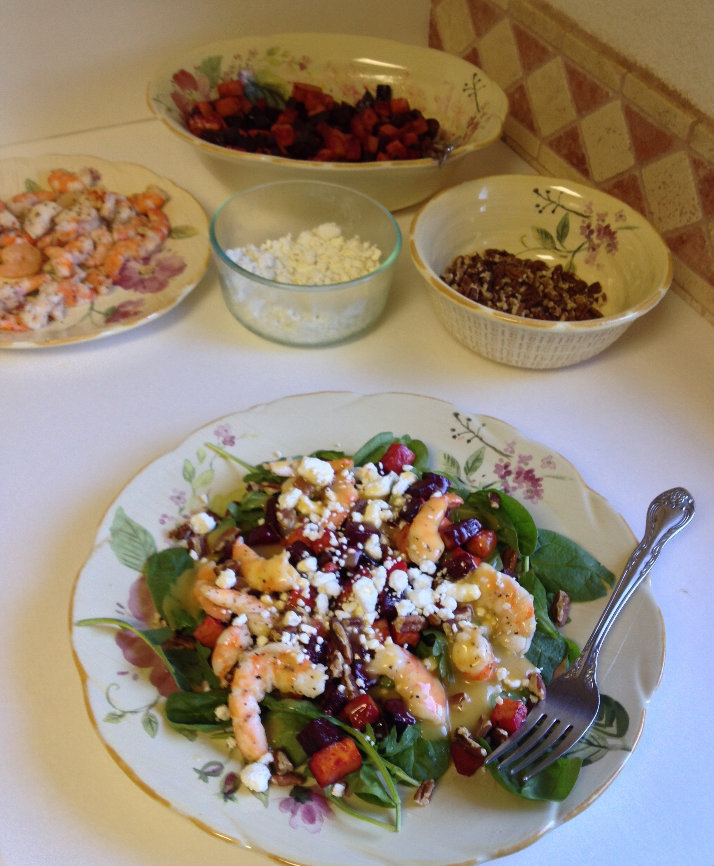 plating leafy greens with other ingredients to make Roasted Beet, Sweet Potato, Mixed Greens and Shrimp Salad.jpg